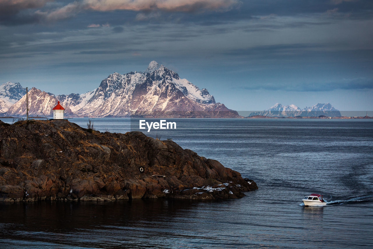 Scenic view of boat in sea by mountains against sky