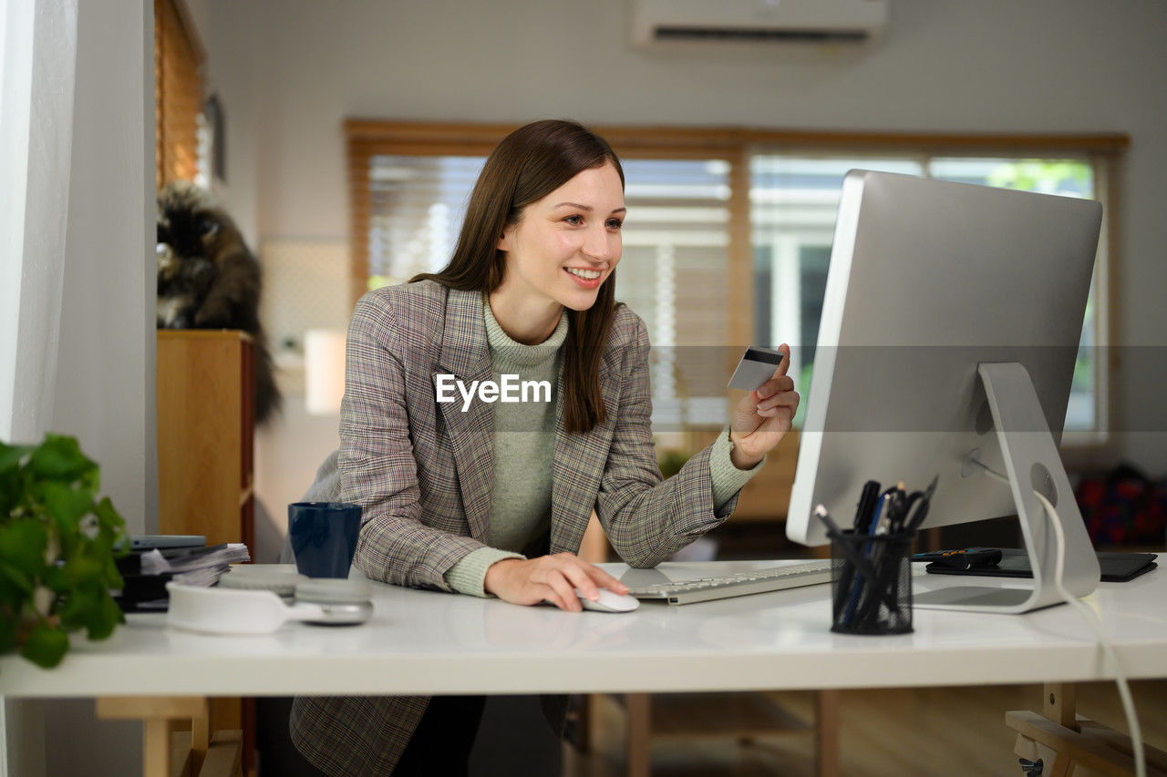 portrait of young woman using laptop at desk in office