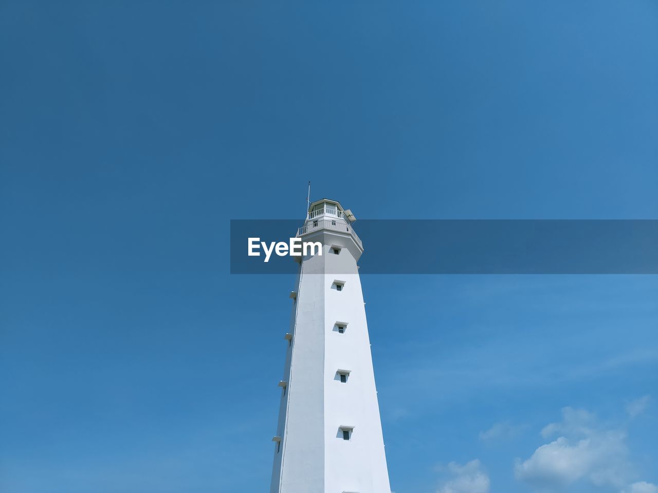 Low angle view of lighthouse by building against clear sky