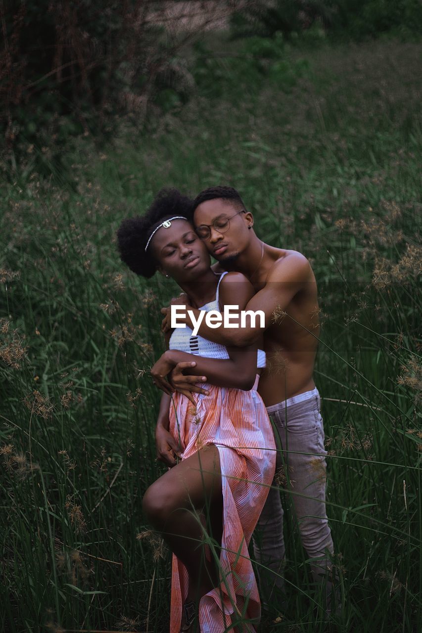 YOUNG COUPLE STANDING IN FIELD