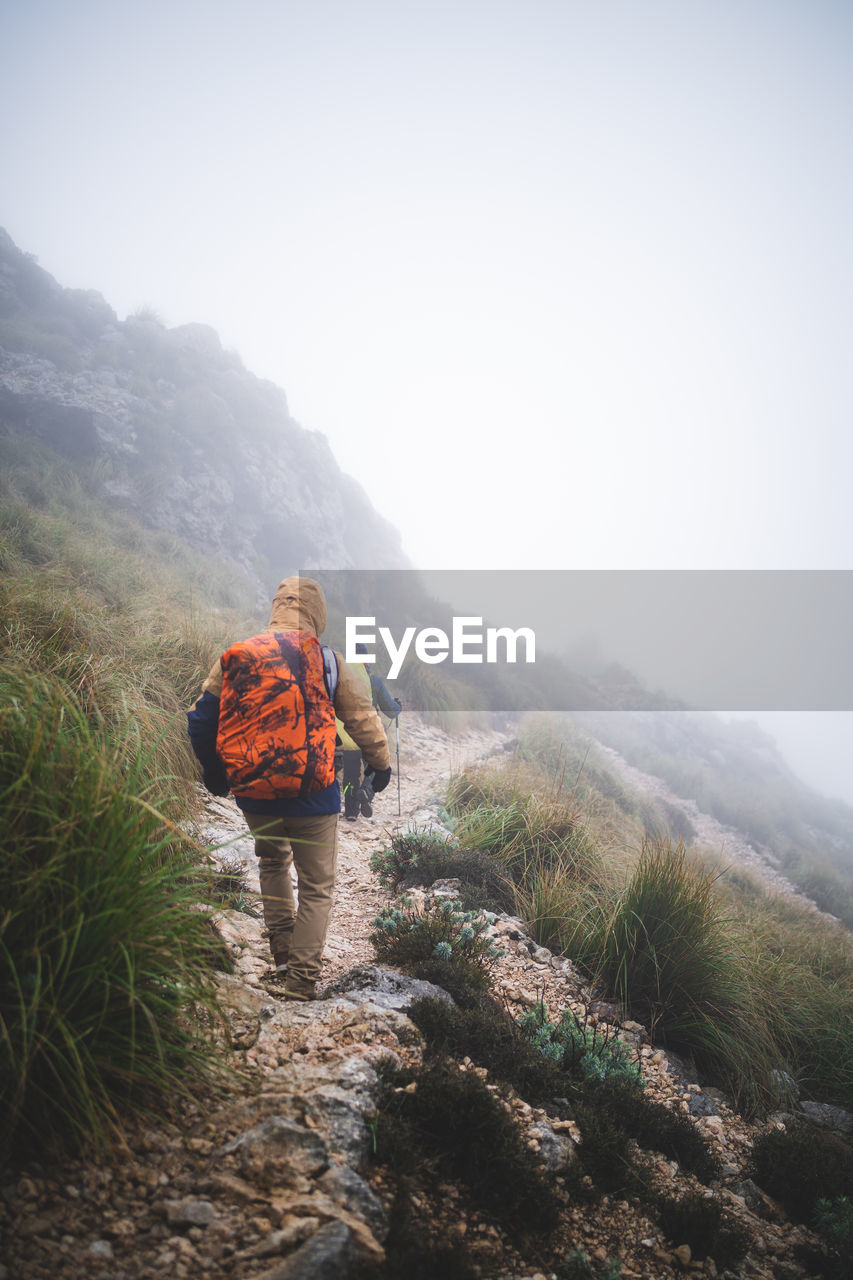 Two hikers walking down through path during foggy day