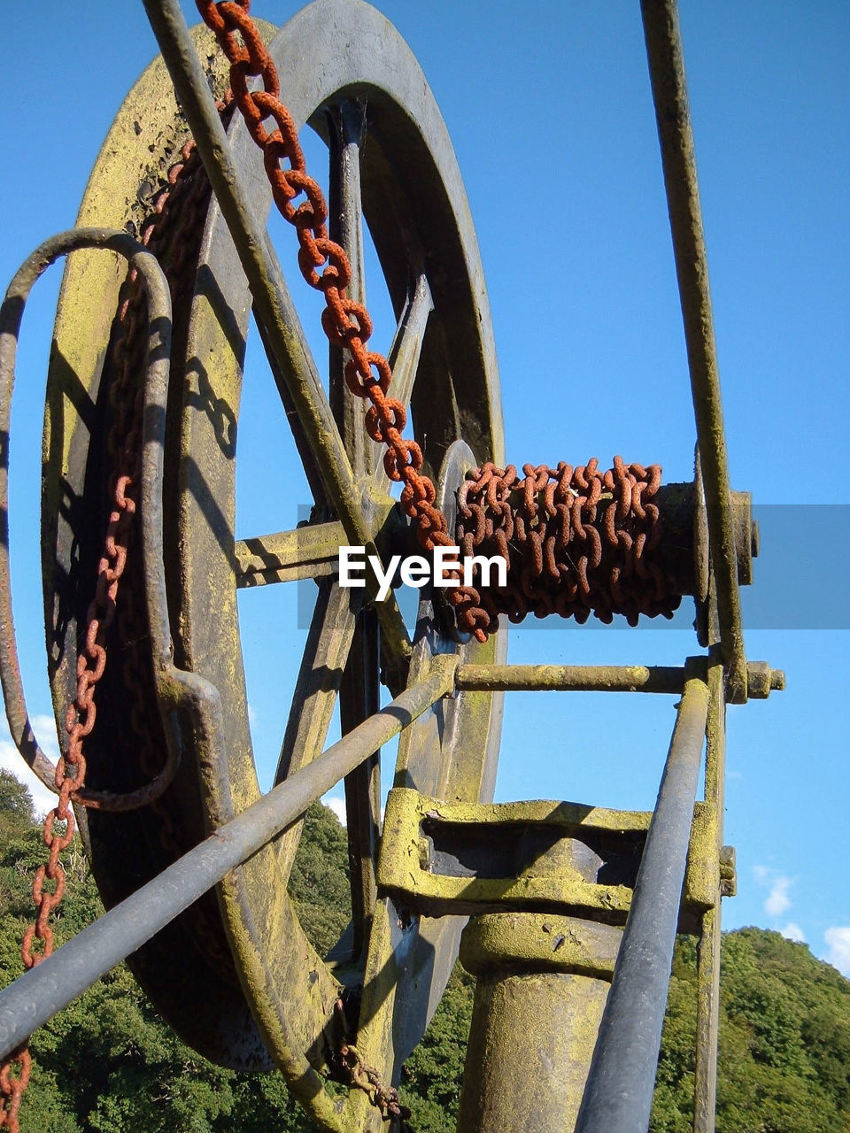 LOW ANGLE VIEW OF RUSTY WHEEL AGAINST SKY