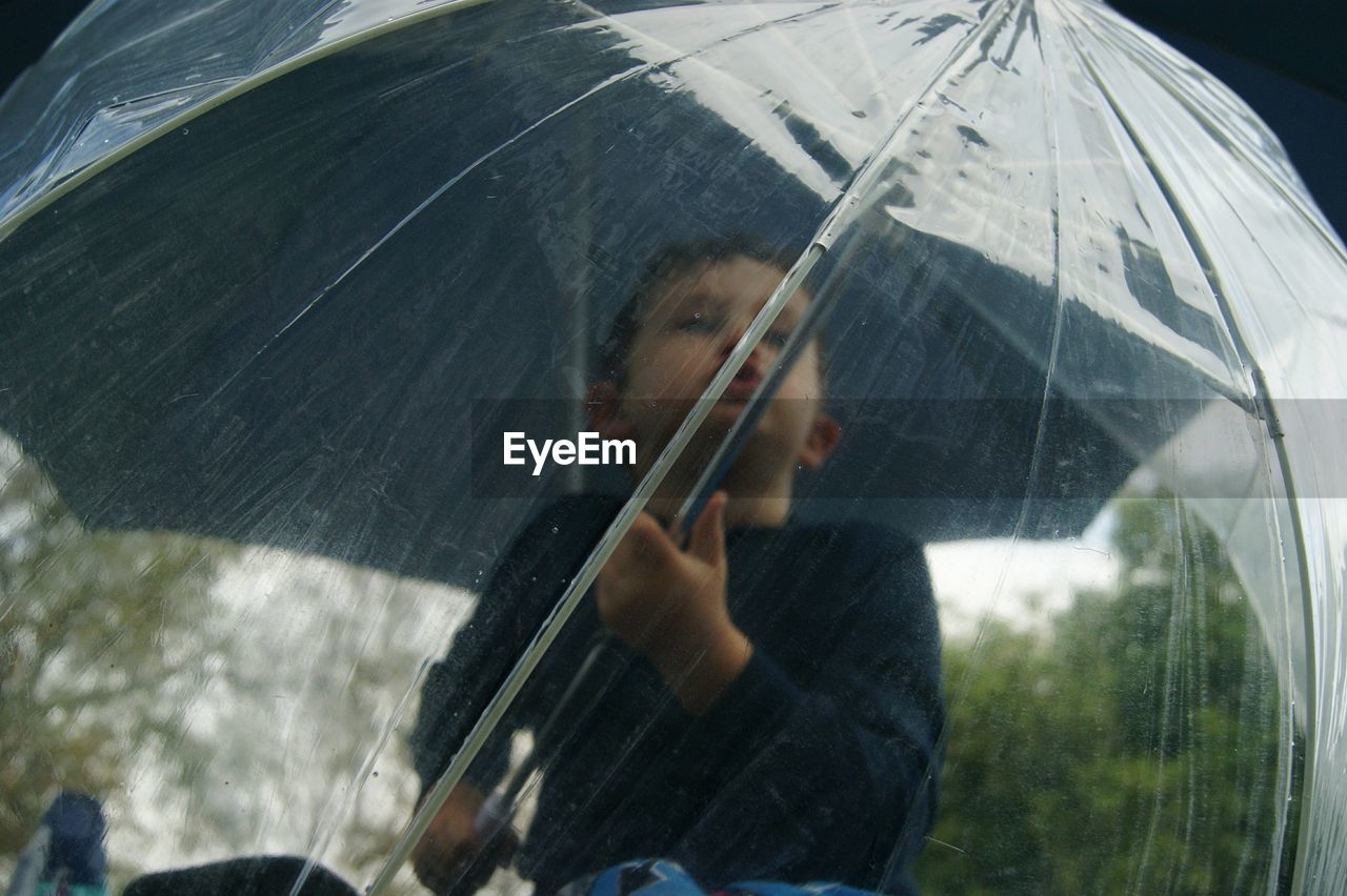 Low angle view of boy holding umbrella during monsoon