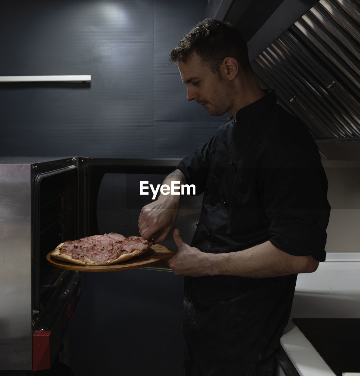 Chef takes the hot pizza out of the oven freshly baked