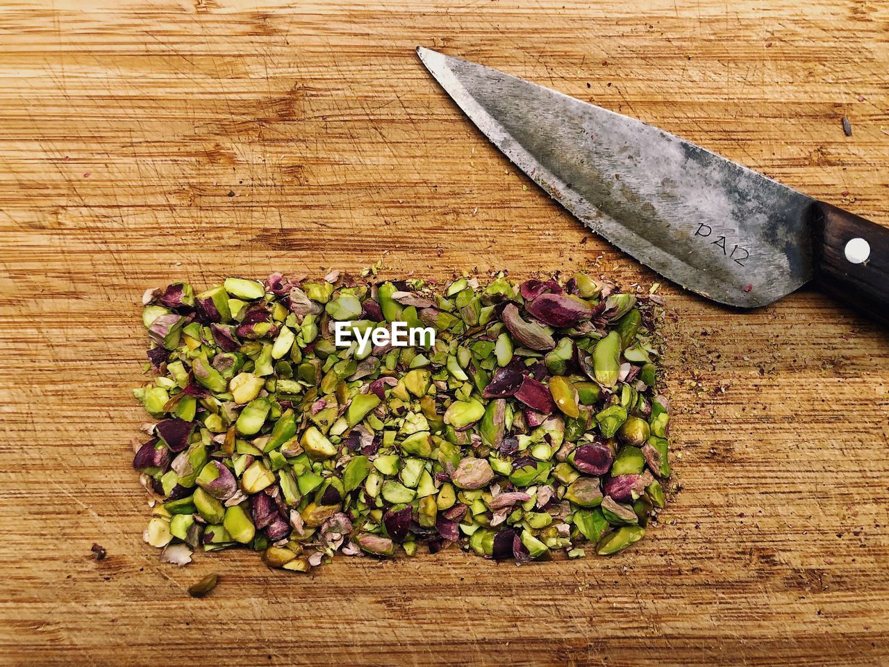 Directly above shot of chopped pistachios by knife on cutting board