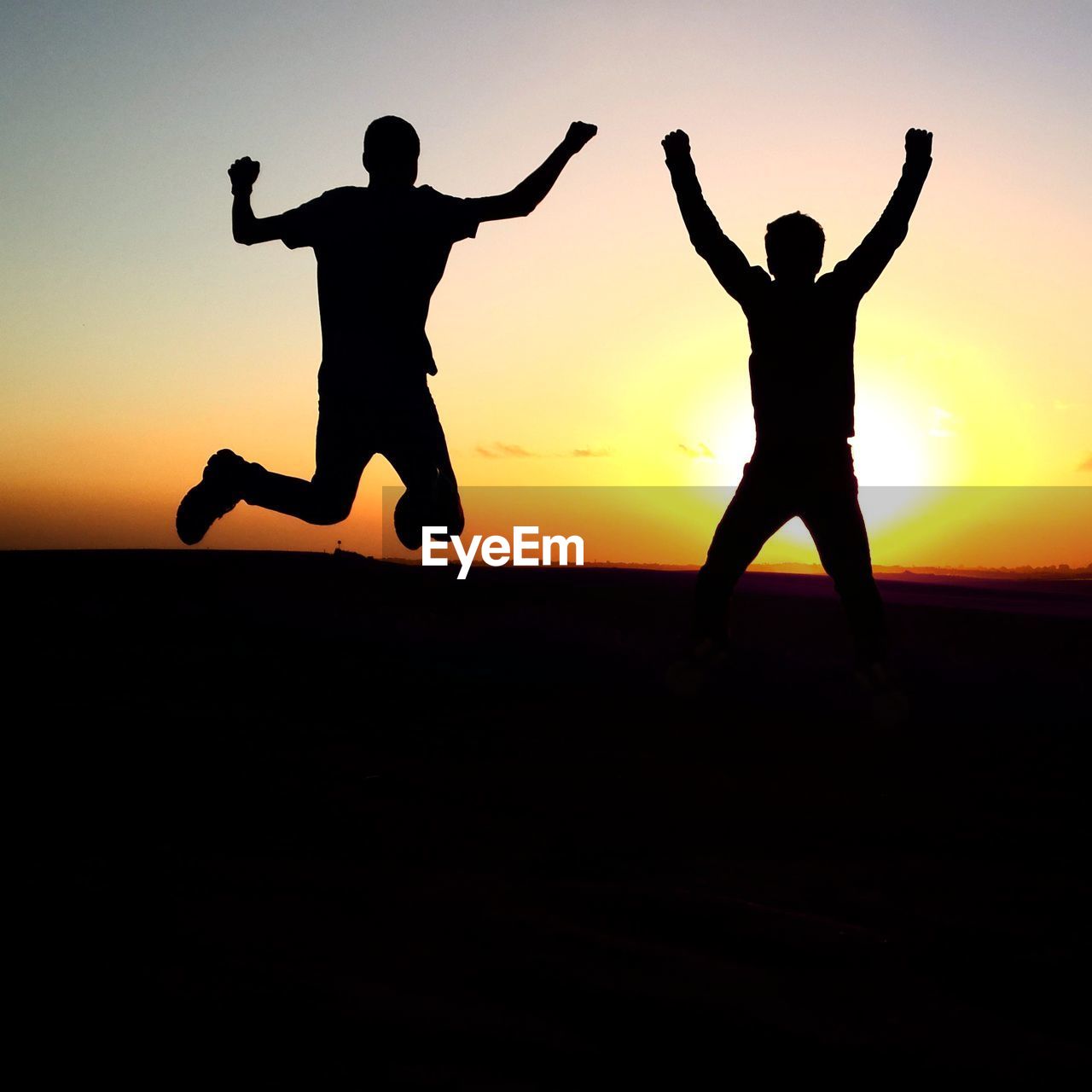 Silhouette men jumping against sky during sunset