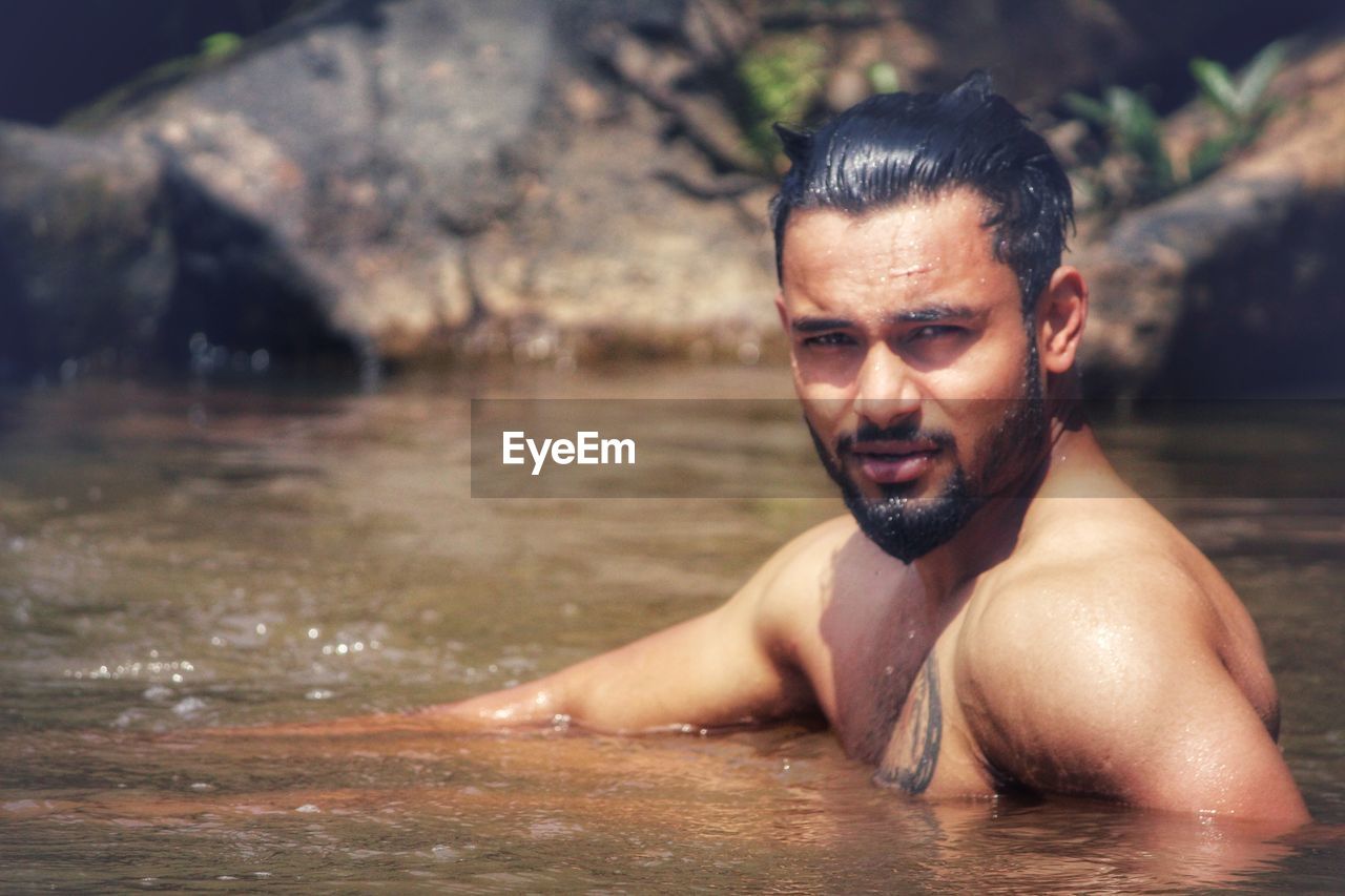 Portrait of shirtless man swimming in lake