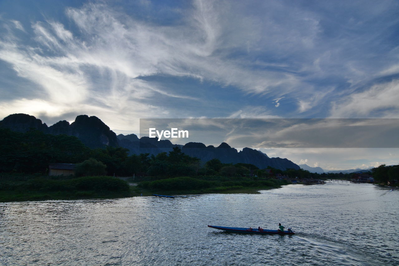 MAN IN BOAT ON WATER AGAINST SKY