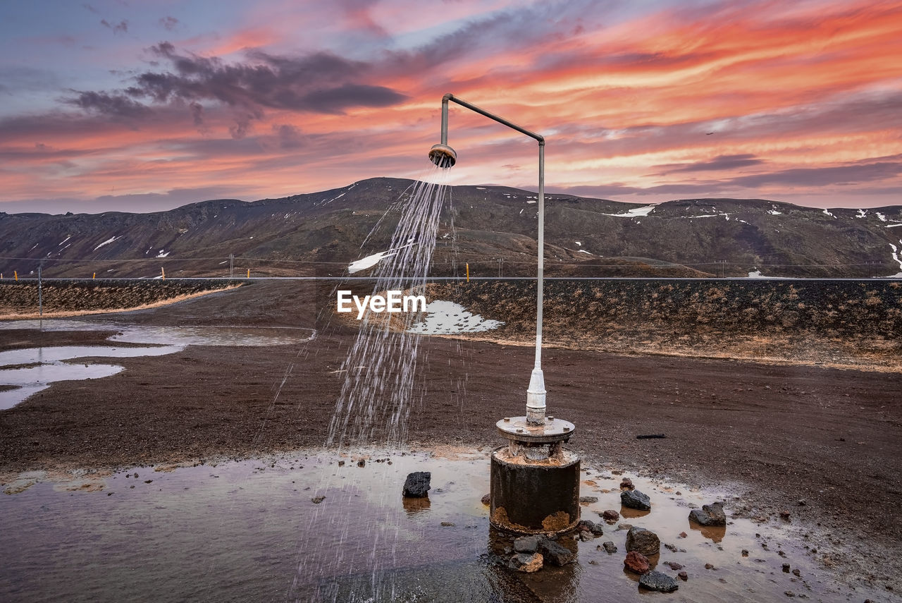 Hot shower station from geothermal power at krafla against mountain during sunset