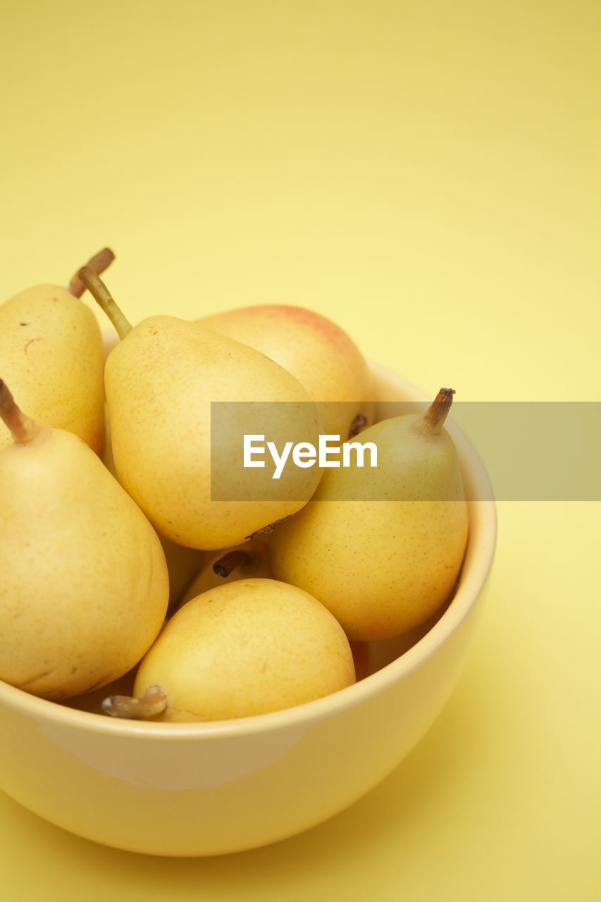 Pears in a yellow bowl on yellow background