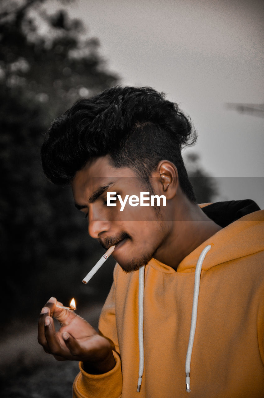 PORTRAIT OF MAN SMOKING CIGARETTE OUTDOORS