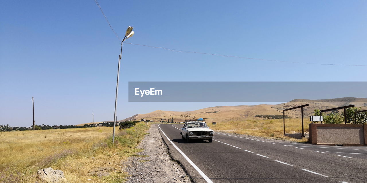 VEHICLES ON ROAD AGAINST CLEAR BLUE SKY