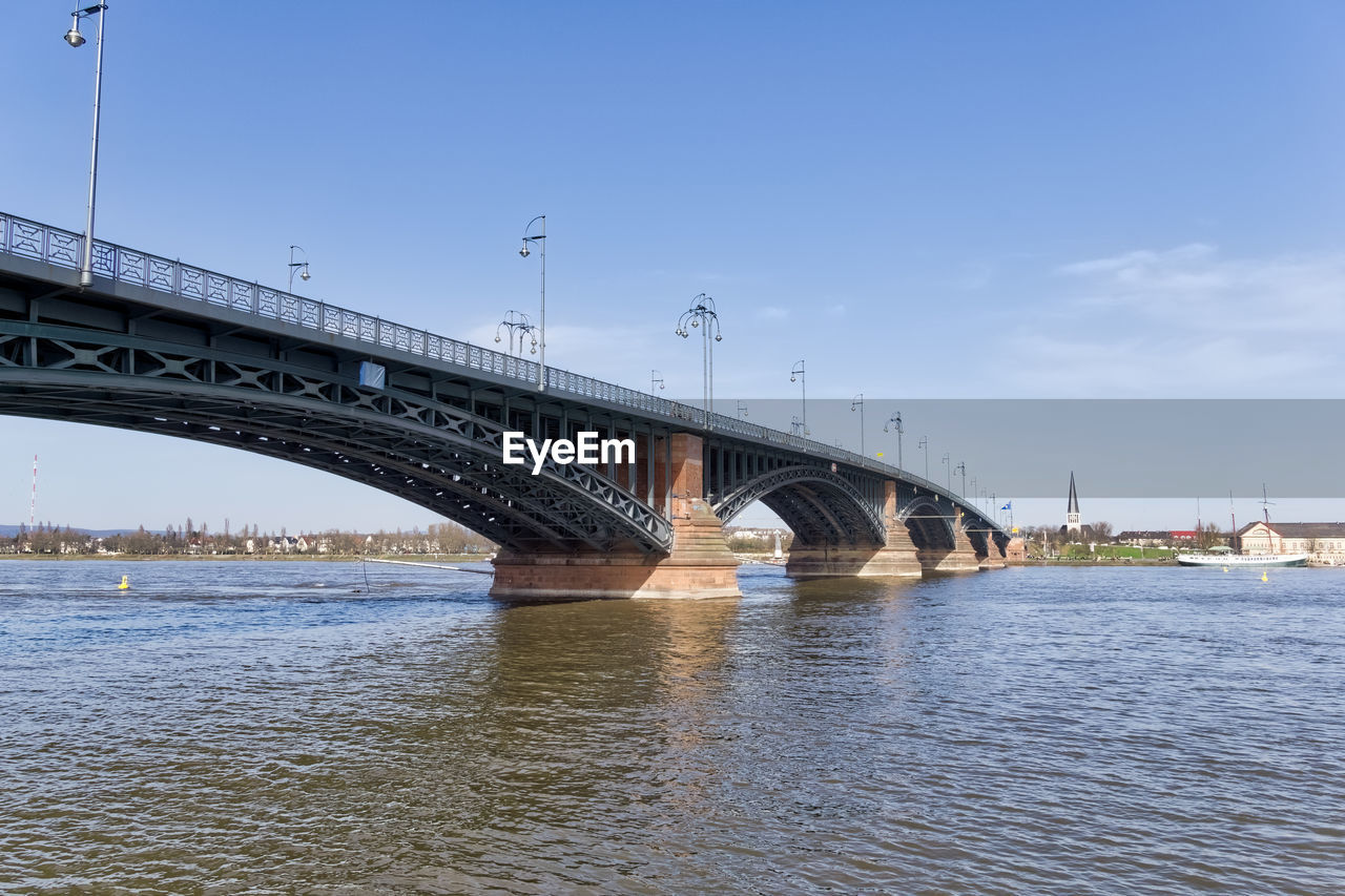 Bridge over river in city against sky