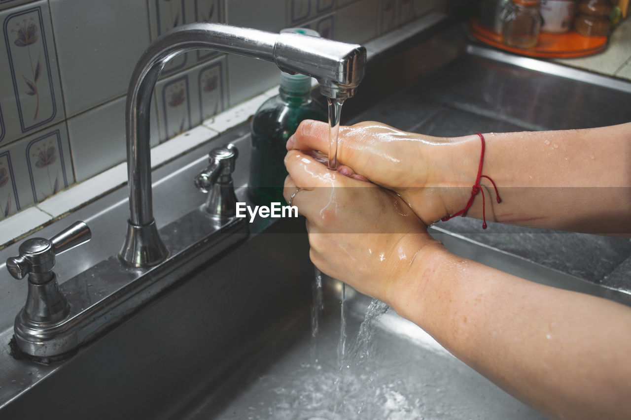 Close-up of person cleaning hands at sink