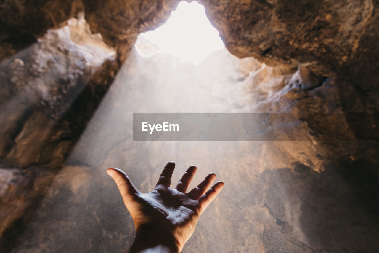 Male hand reaching towards the light. feeling hopeful.