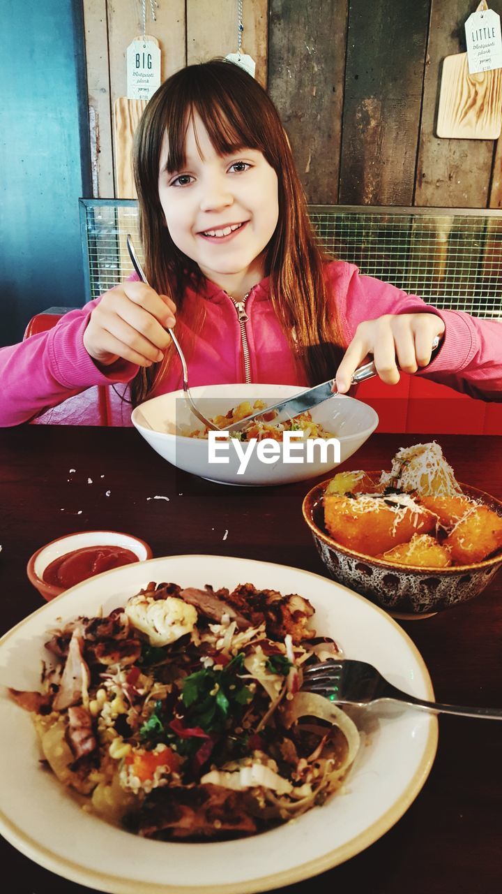 PORTRAIT OF GIRL EATING ICE CREAM ON TABLE