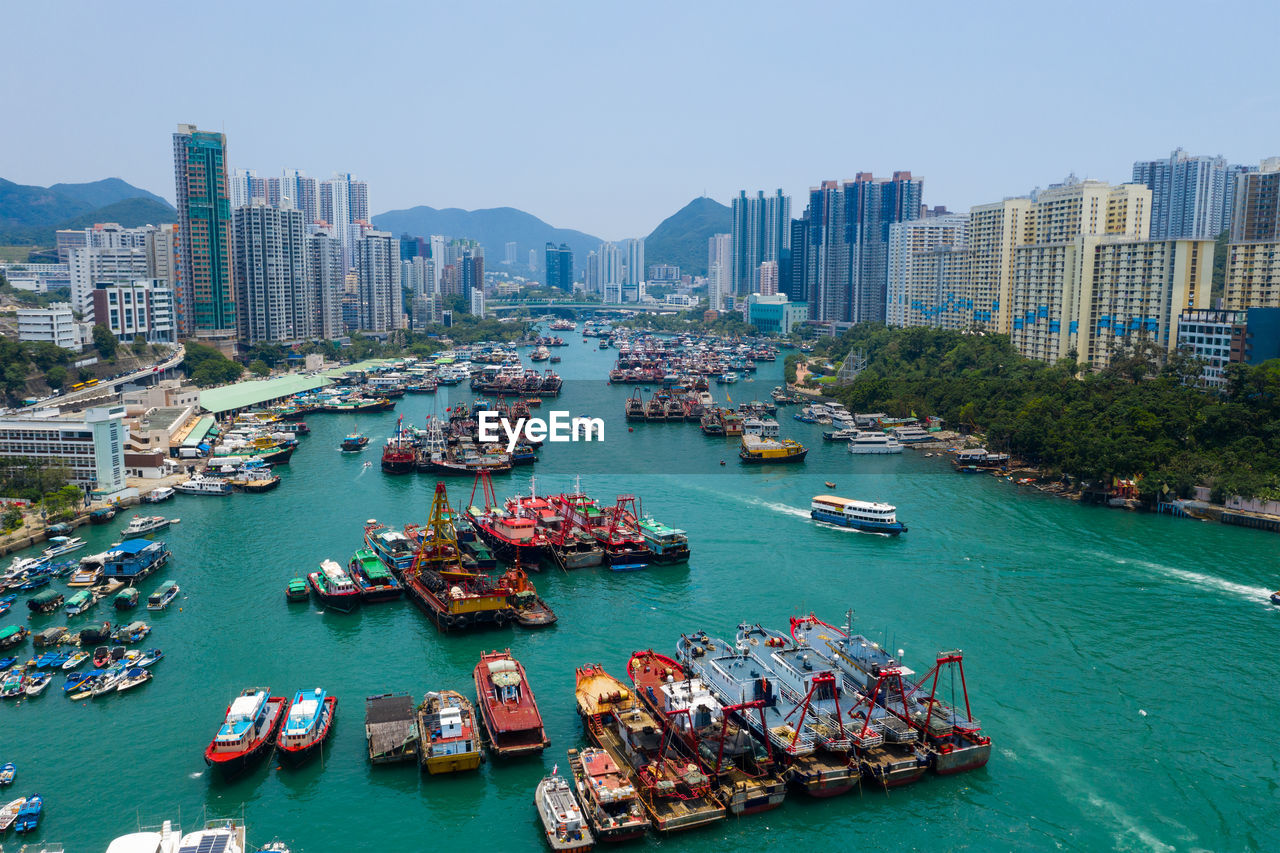 High angle view of boats in river by cityscape against sky