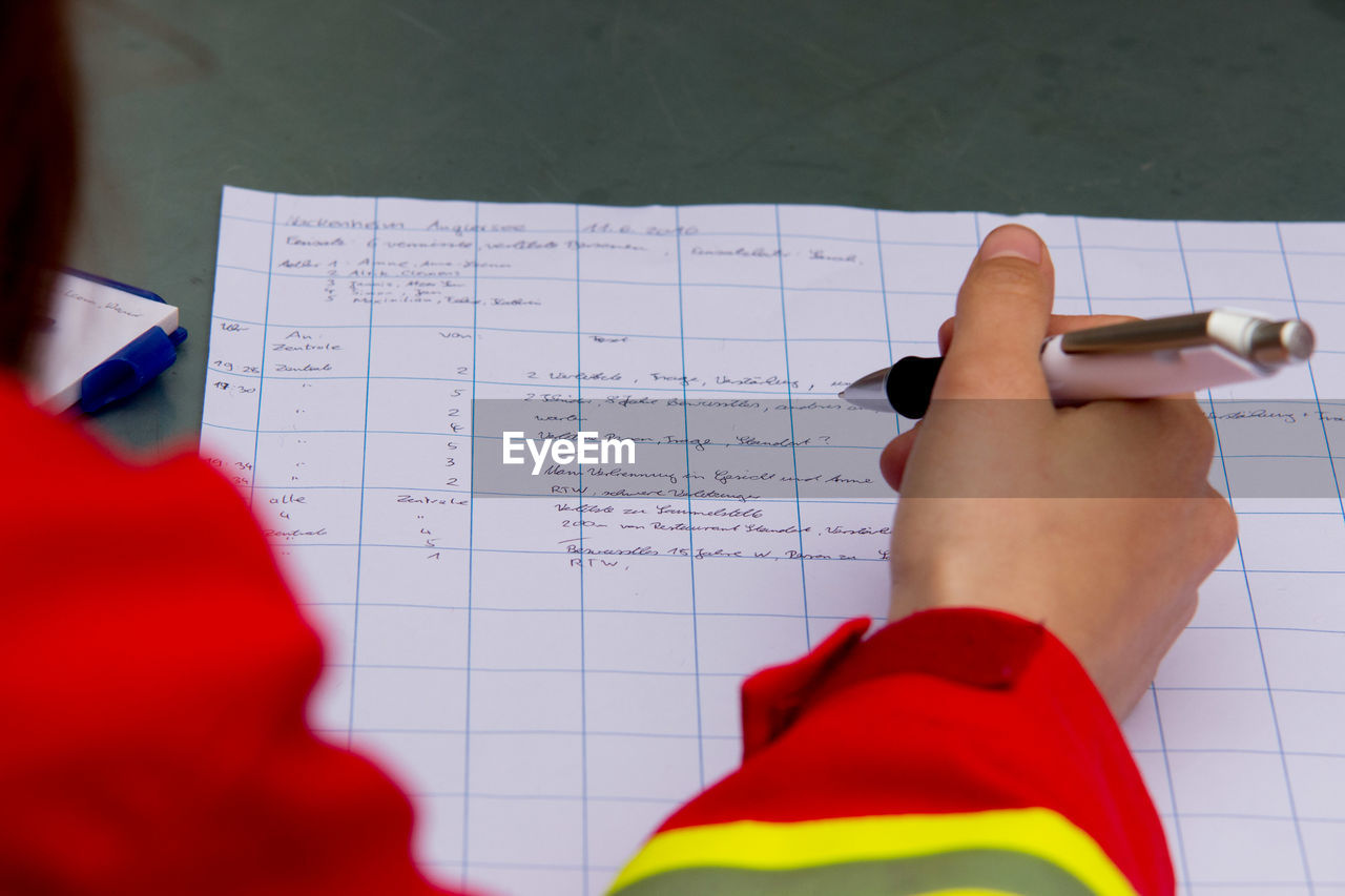 Cropped image of person writing on paper at table