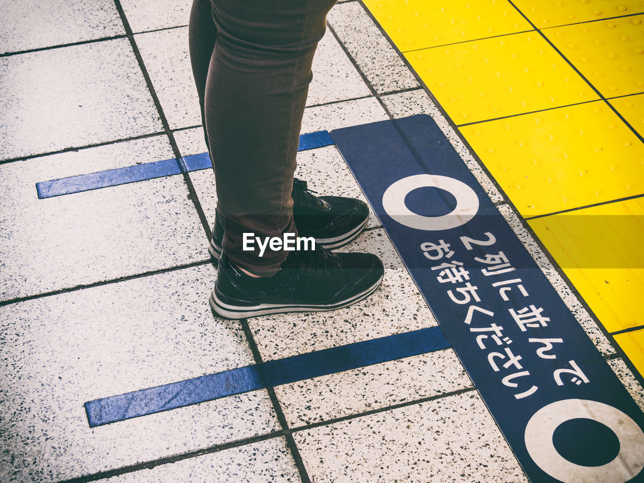 LOW SECTION OF PERSON STANDING ON TILED FLOOR