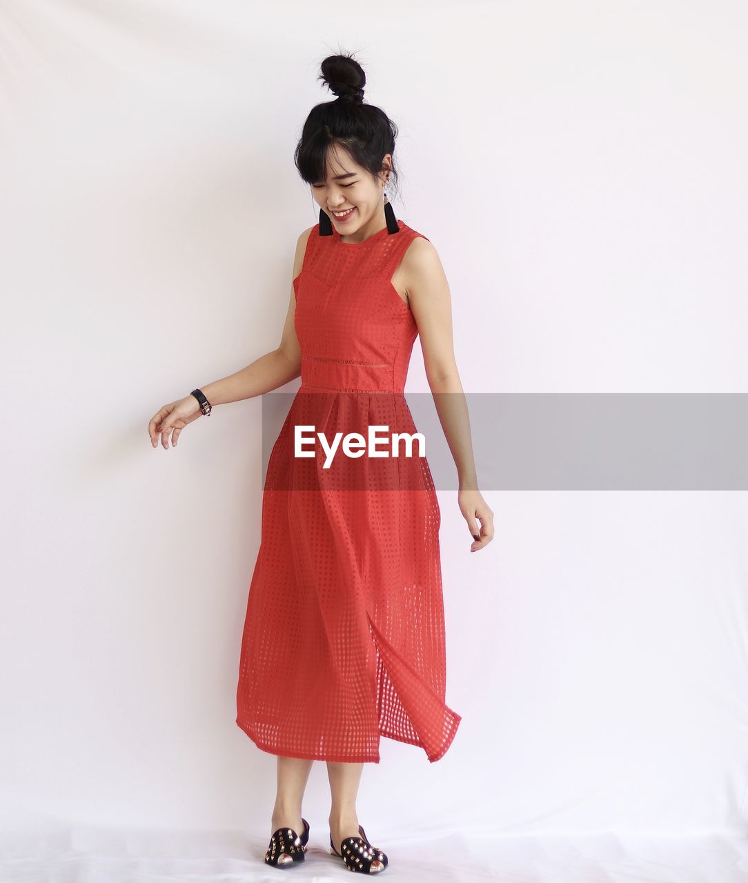 Portrait of a smiling young woman in red dress against white background