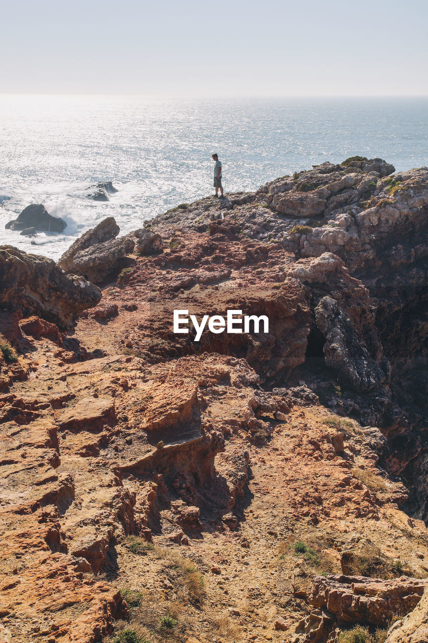 Man standing on rock formation against sea