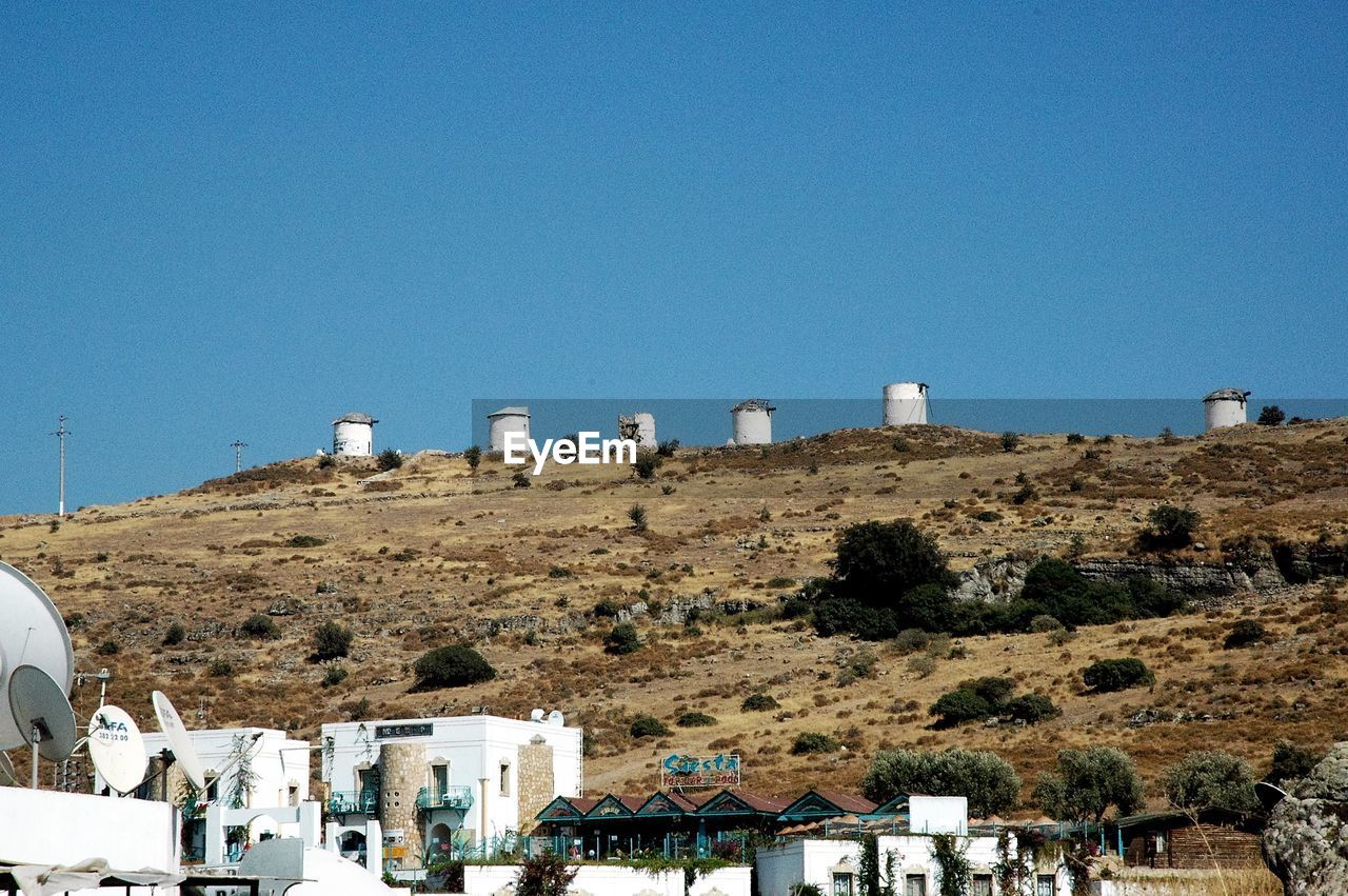 Low angle view of tanks on hill against clear sky