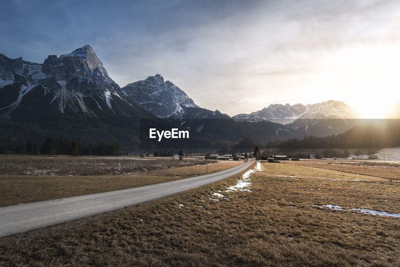 Empty road leading towards snowcapped mountains against sky