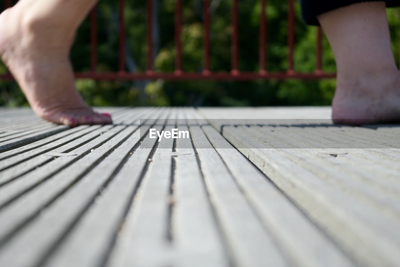 CLOSE-UP LOW SECTION OF MAN STANDING ON WOOD