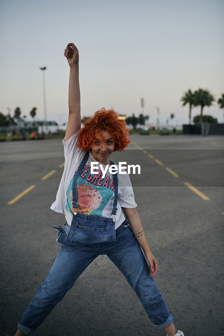 Young happy redhead girl dancing in the street