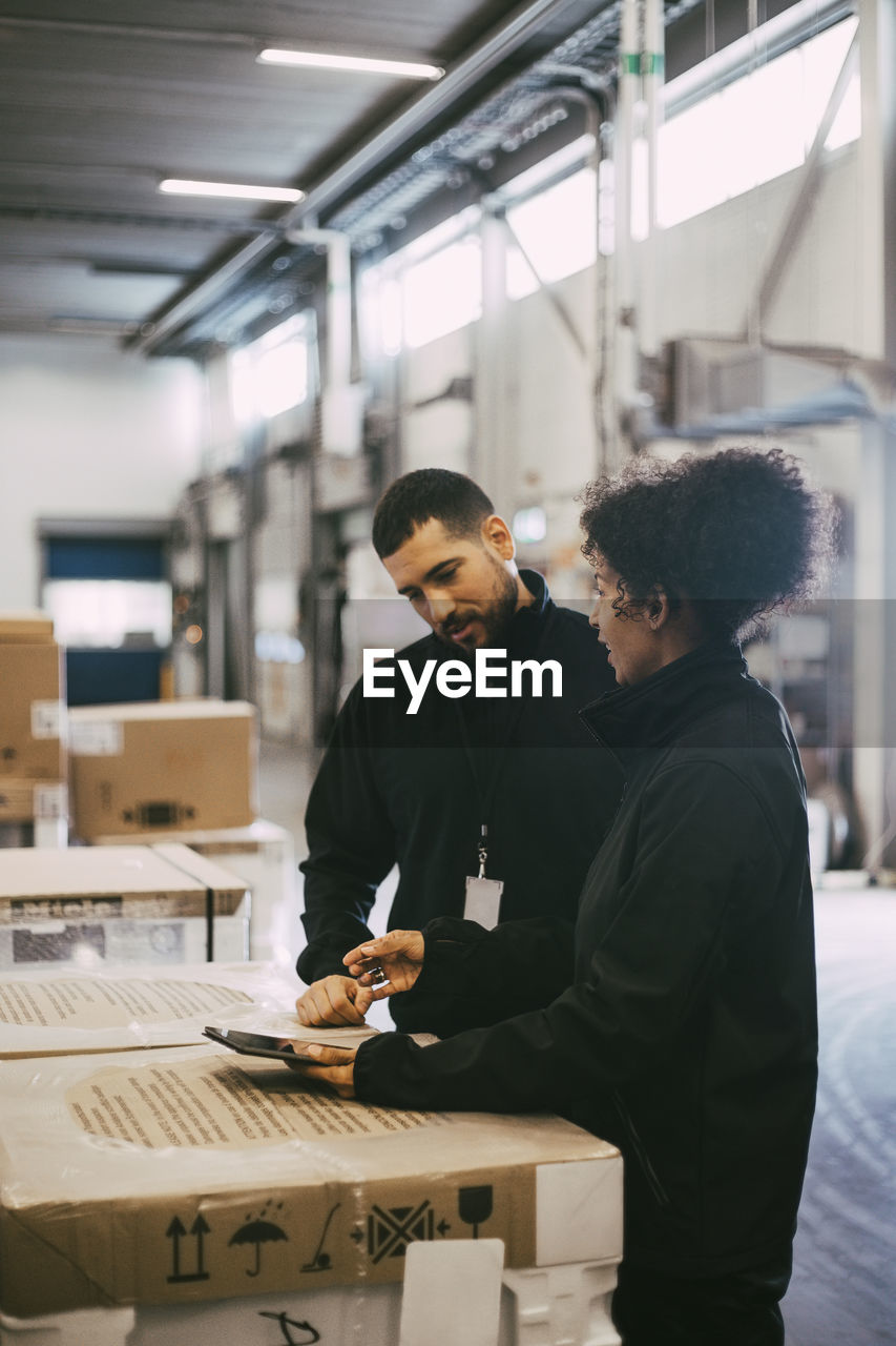 Female entrepreneur discussing with male colleague over digital tablet at warehouse