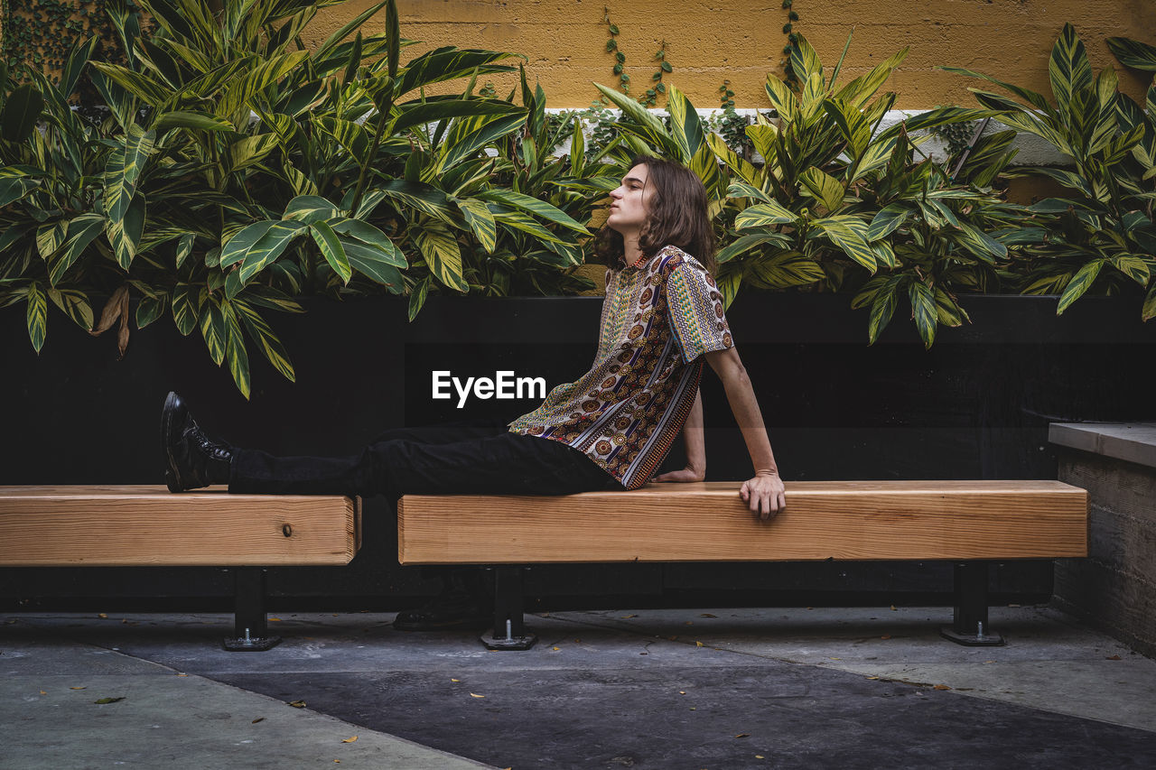 WOMAN SITTING ON BENCH AT PLANTS