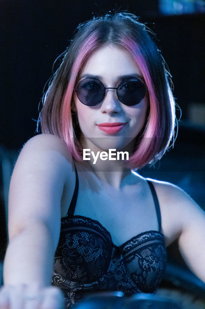 fashion, one person, glasses, sunglasses, portrait, blue, women, adult, young adult, hairstyle, looking at camera, arts culture and entertainment, eyewear, vision care, clothing, night, make-up, long hair, indoors, front view, cool attitude, female, lifestyles, headshot, waist up, person, blond hair, human hair, nightlife, human face