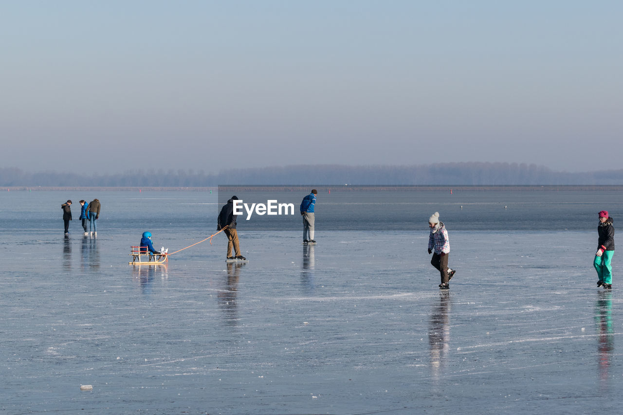 People at beach against sky