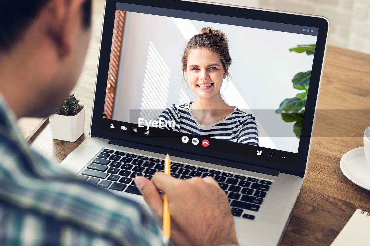 Midsection of man talking on video call at cafe