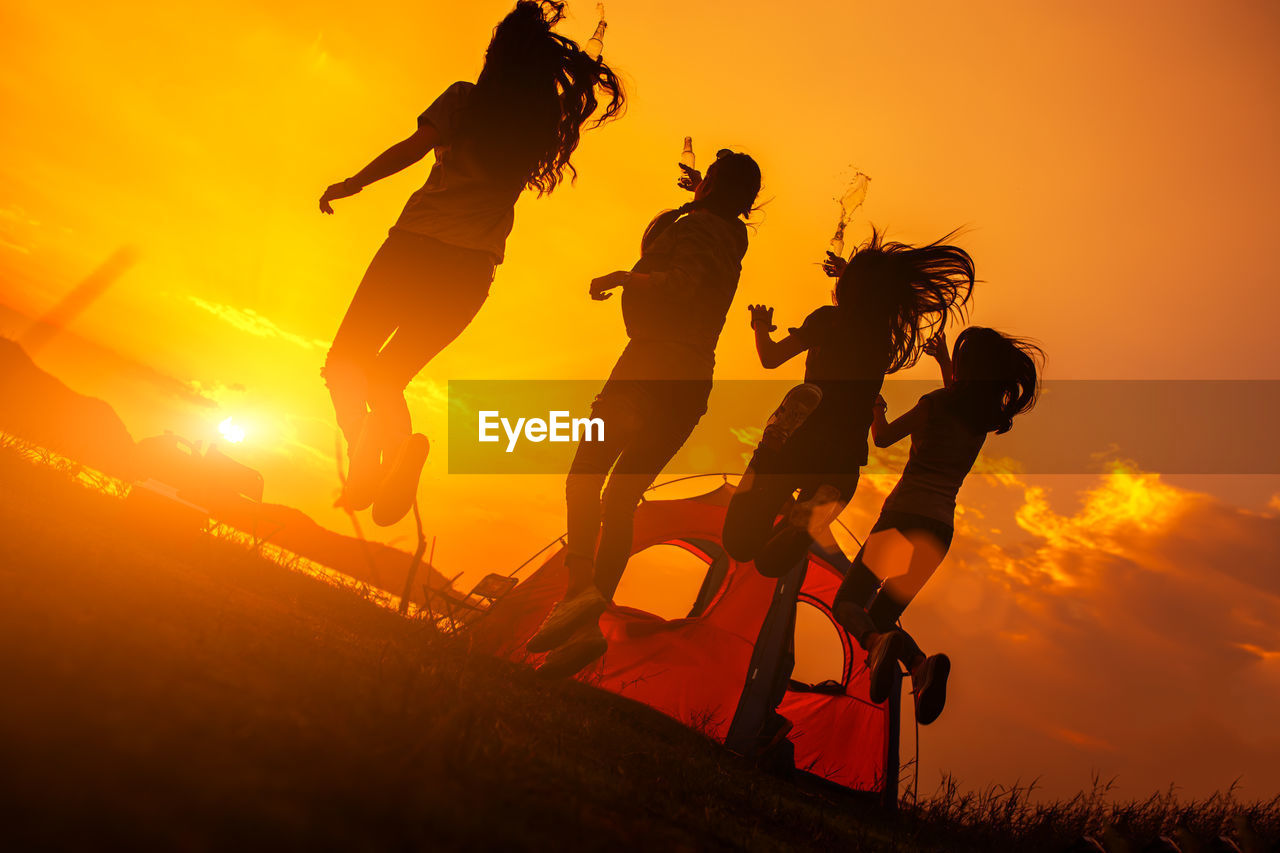 Happy friends enjoying camping at beach during sunset