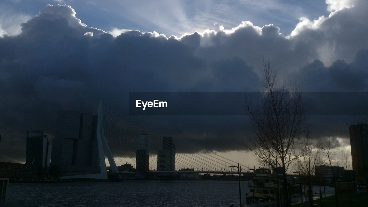 Low angle view of erasmus bridge over river against cloudy sky