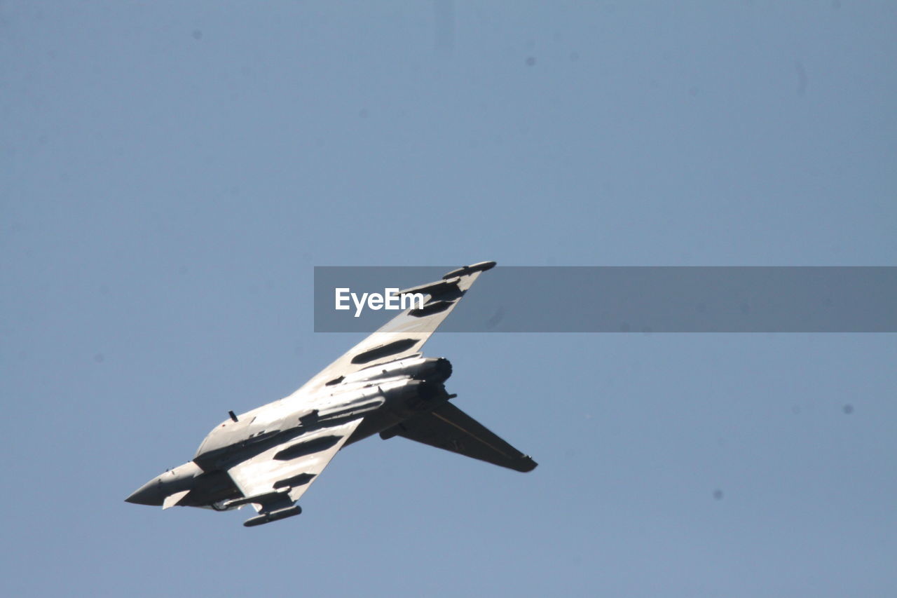 LOW ANGLE VIEW OF AIRPLANE FLYING IN CLEAR SKY