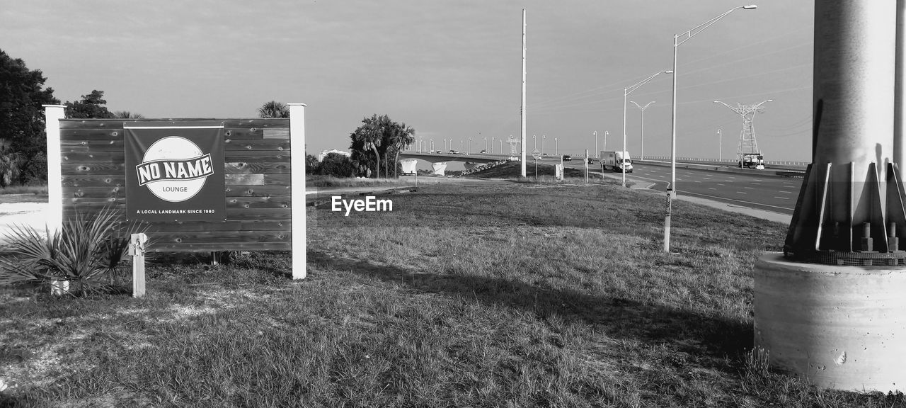 black and white, monochrome photography, monochrome, sign, plant, communication, nature, grass, sky, no people, day, road, road sign, white, tree, text, land, information sign, outdoors, black, warning sign, western script, urban area, architecture