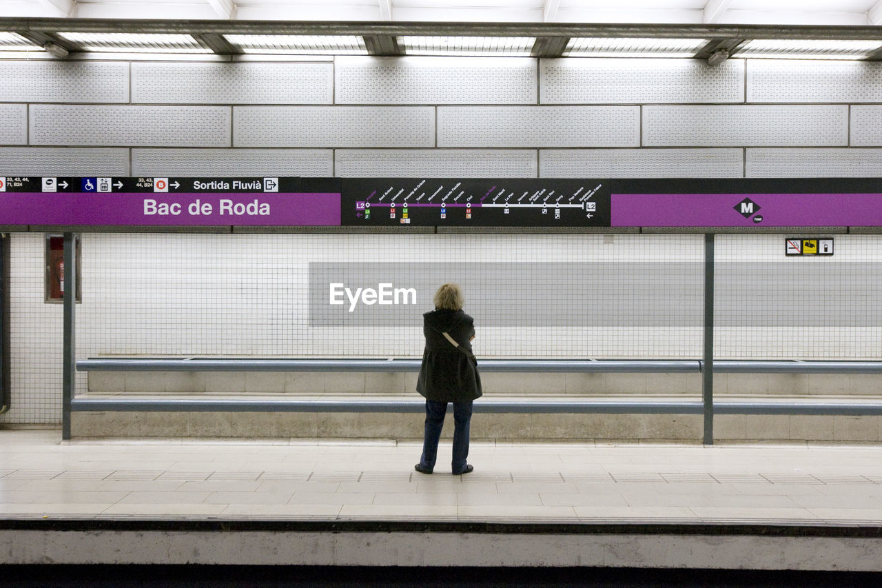 Rear view of woman standing at subway station