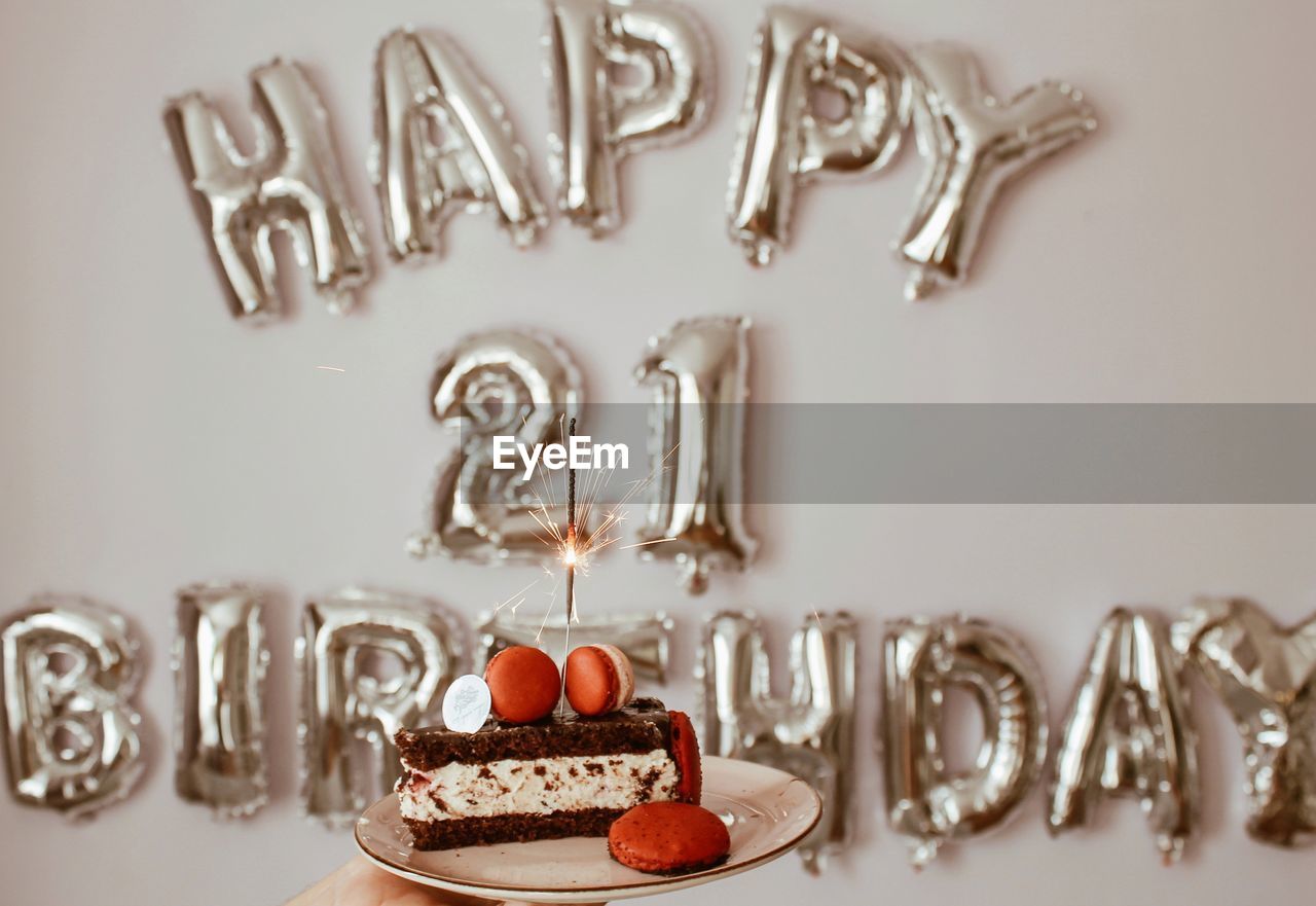 Close-up of cake with sparklers against text on wall