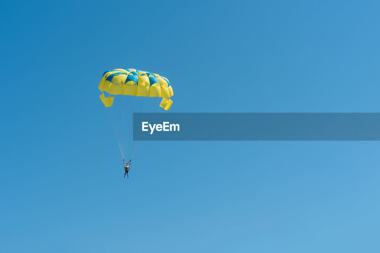 LOW ANGLE VIEW OF KITE FLYING AGAINST BLUE SKY