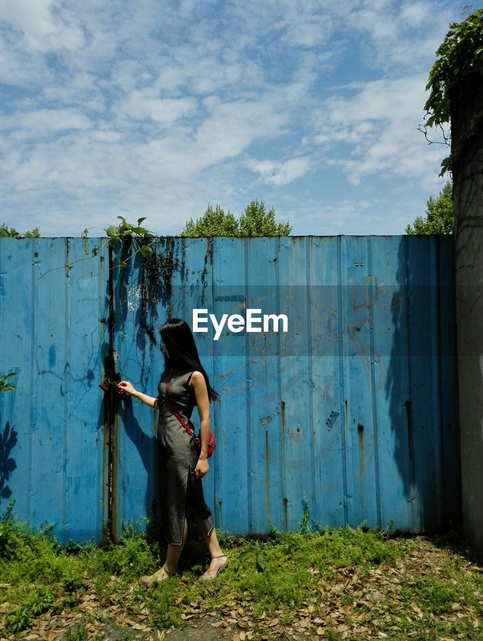 Full length of woman standing by gate on land