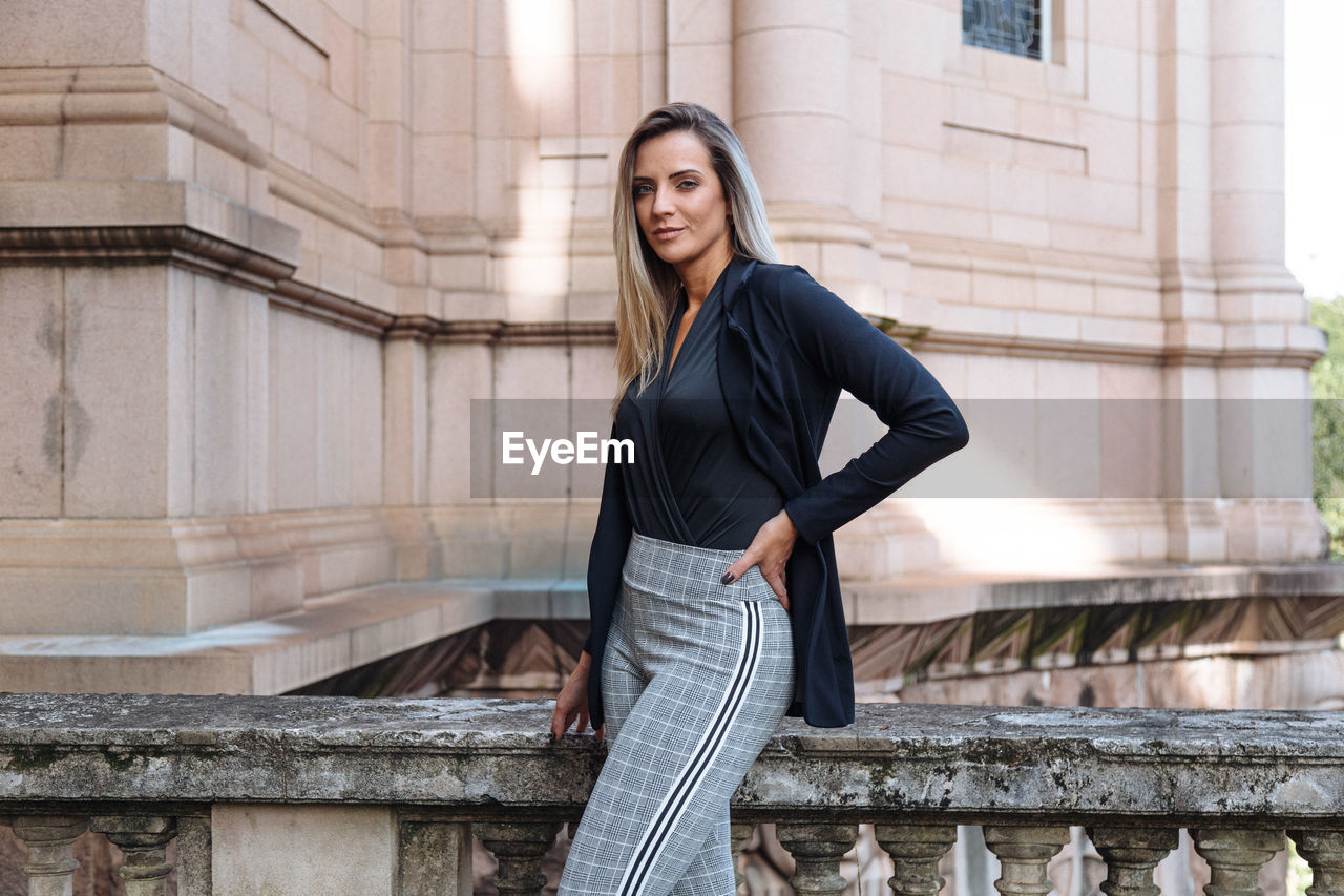 Portrait of woman standing against building