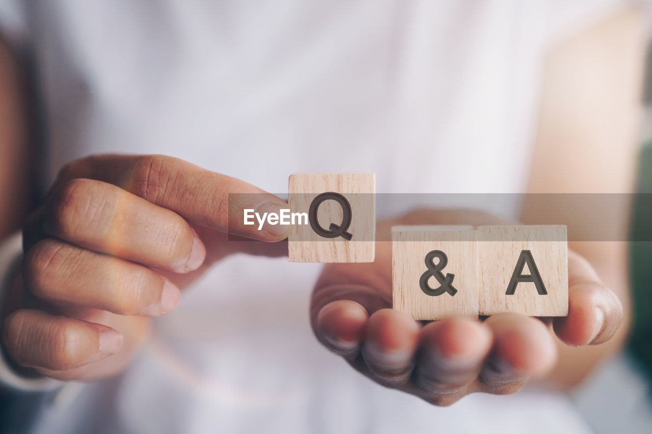 Q and a alphabet on wooden cube in hand hold with background. question and answer meaning concept.