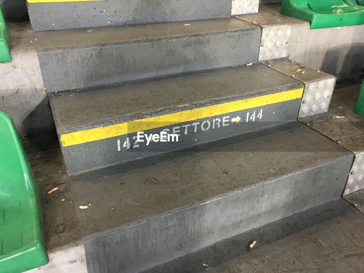 HIGH ANGLE VIEW OF YELLOW TEXT ON CONCRETE