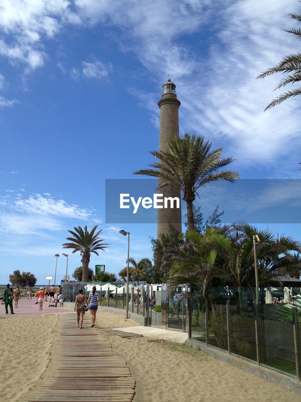 Lighthouse at beach against blue sky