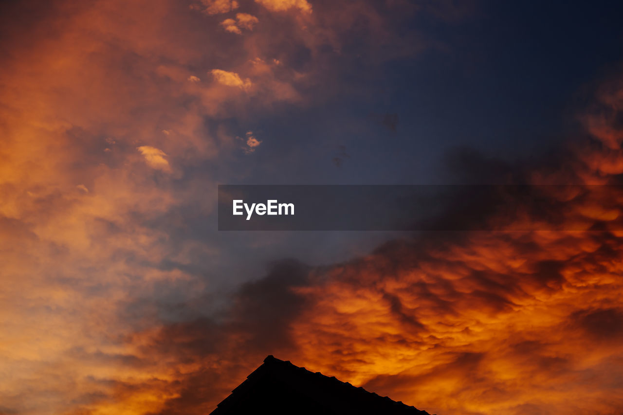 LOW ANGLE VIEW OF DRAMATIC SKY OVER SILHOUETTE OF ORANGE CLOUDS