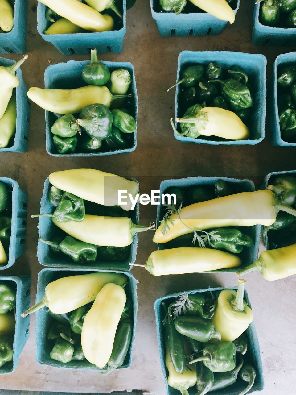 Directly above shot of green peppers in box on table for sale in market