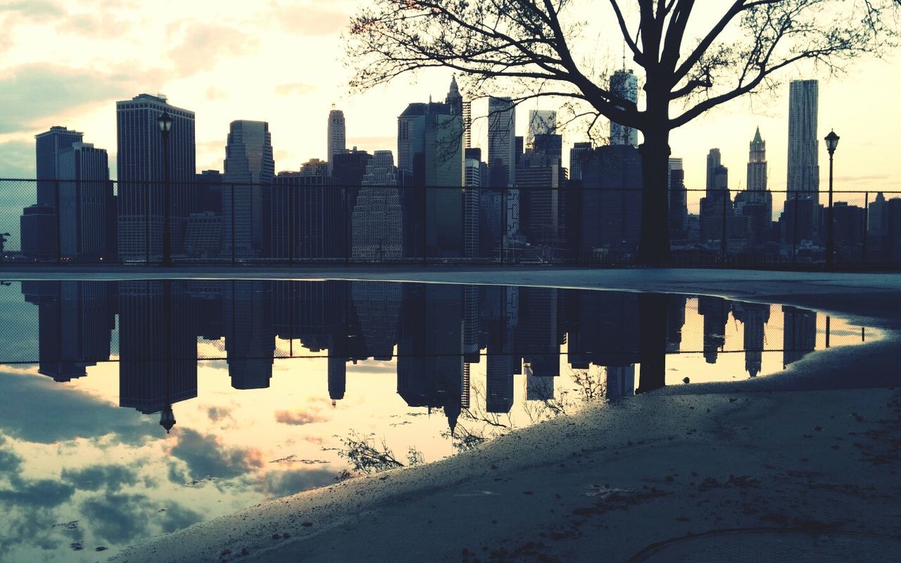 Reflection of buildings in calm water against sky