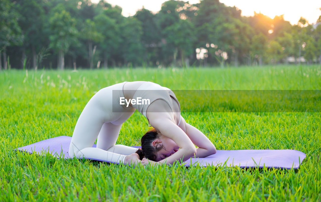 full length of young woman exercising on field